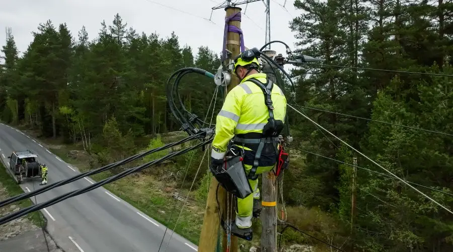 Mann som jobber i en strømstolpe